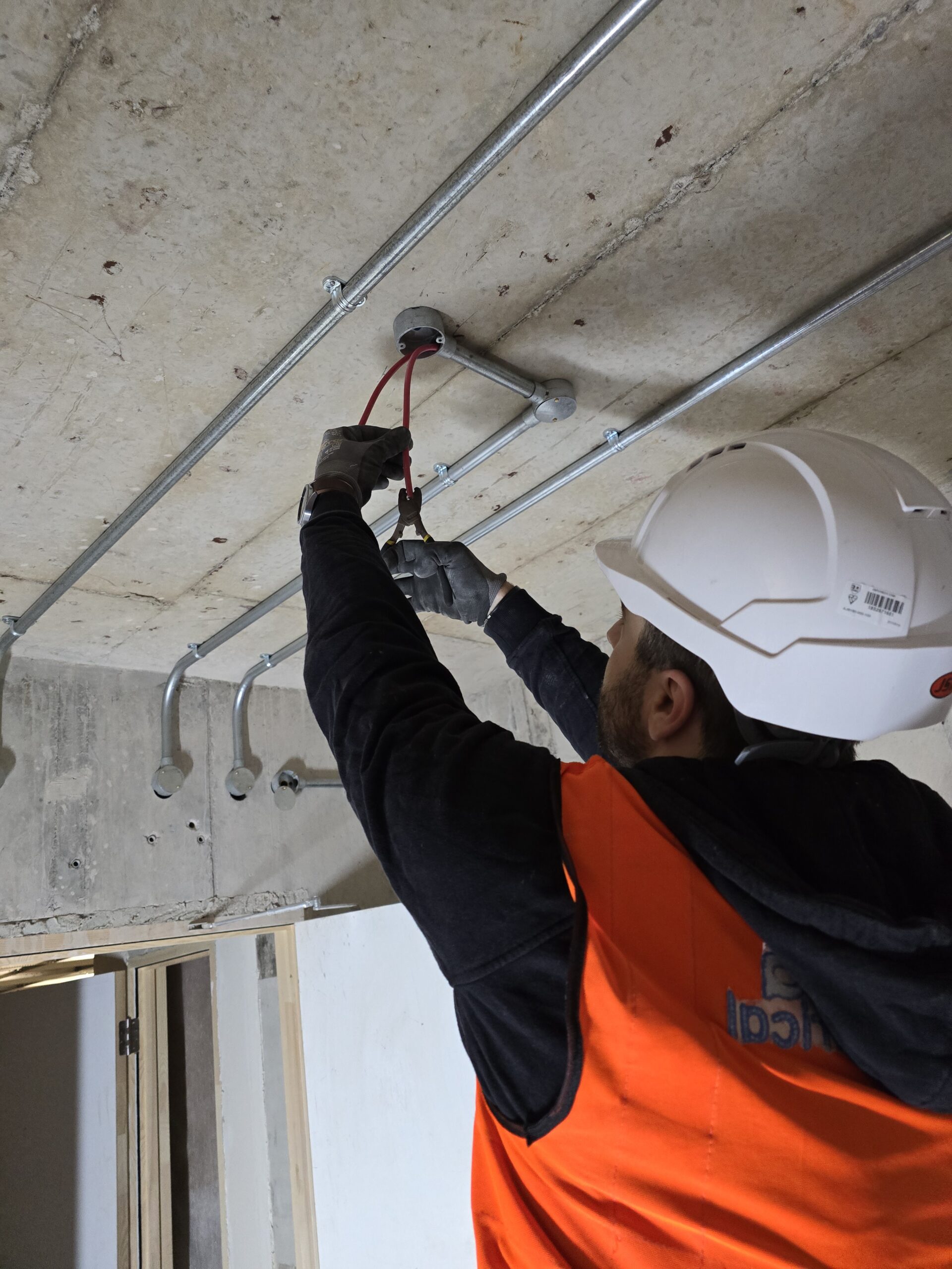 Electrician installing metal conduit containment for a commercial electrical installation