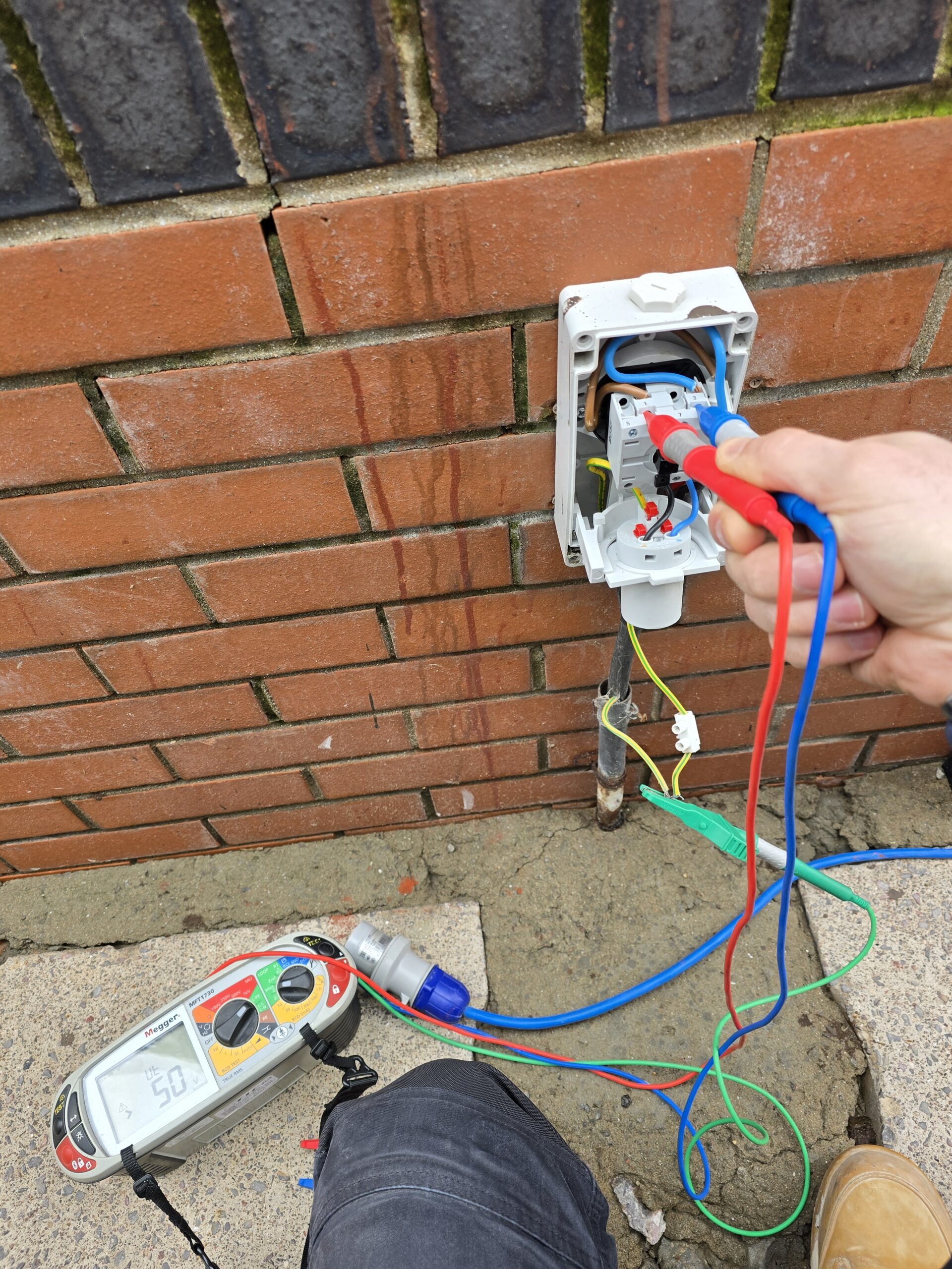 Electrician carrying out fault finding on a 16A caravan supply socket using professional test equipment