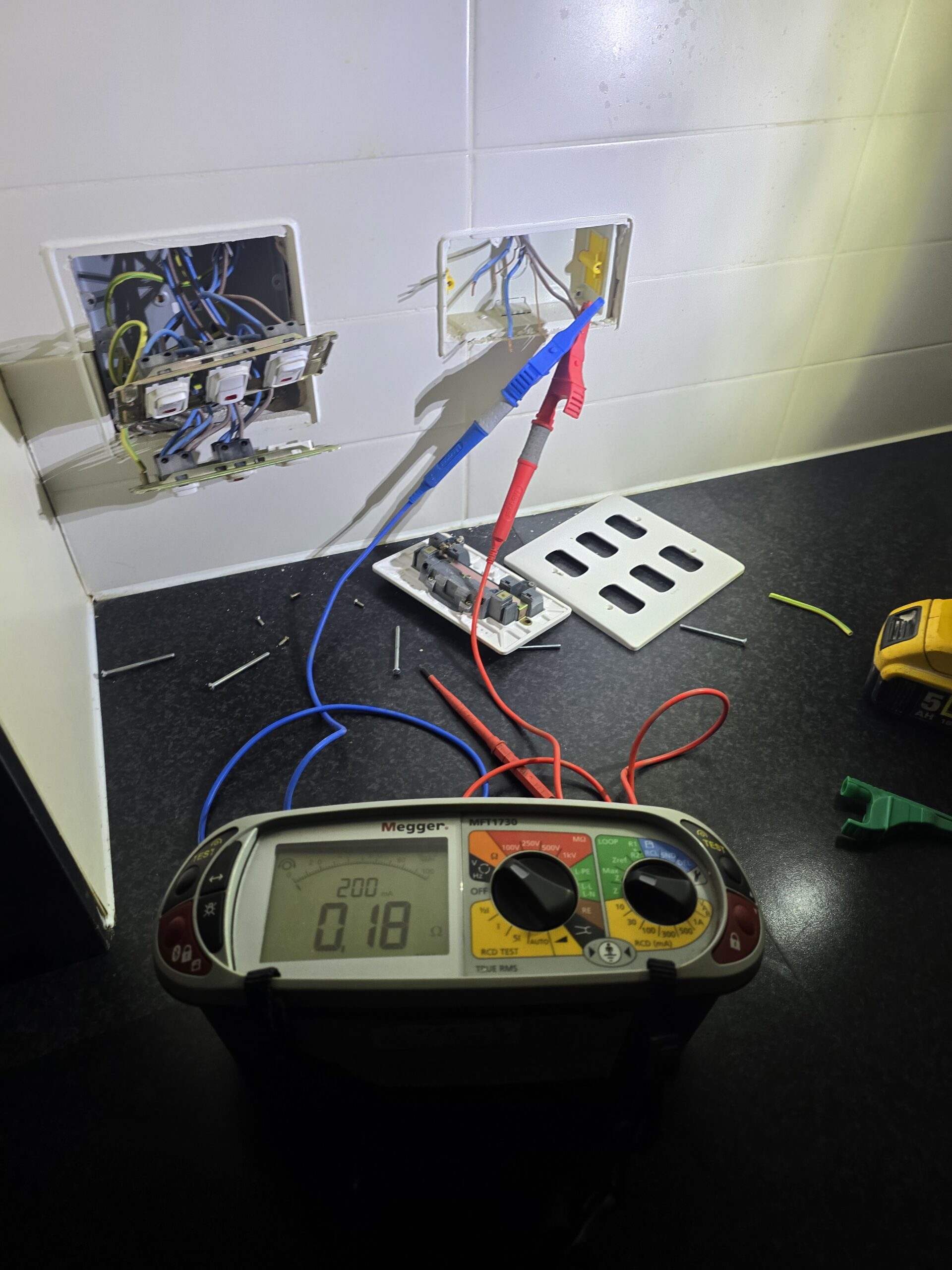 Electrician carrying out fault finding on socket circuits using electrical test equipment
